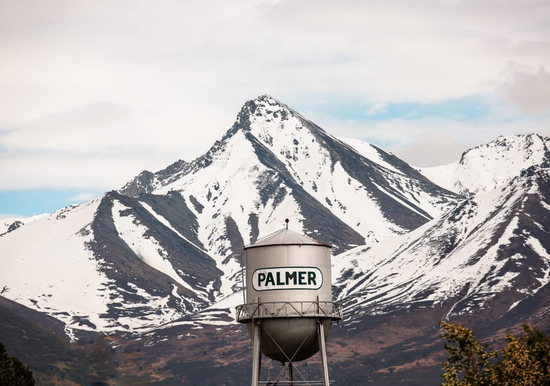 Three people collaborate around a table, examining a blueprint and color samples.
