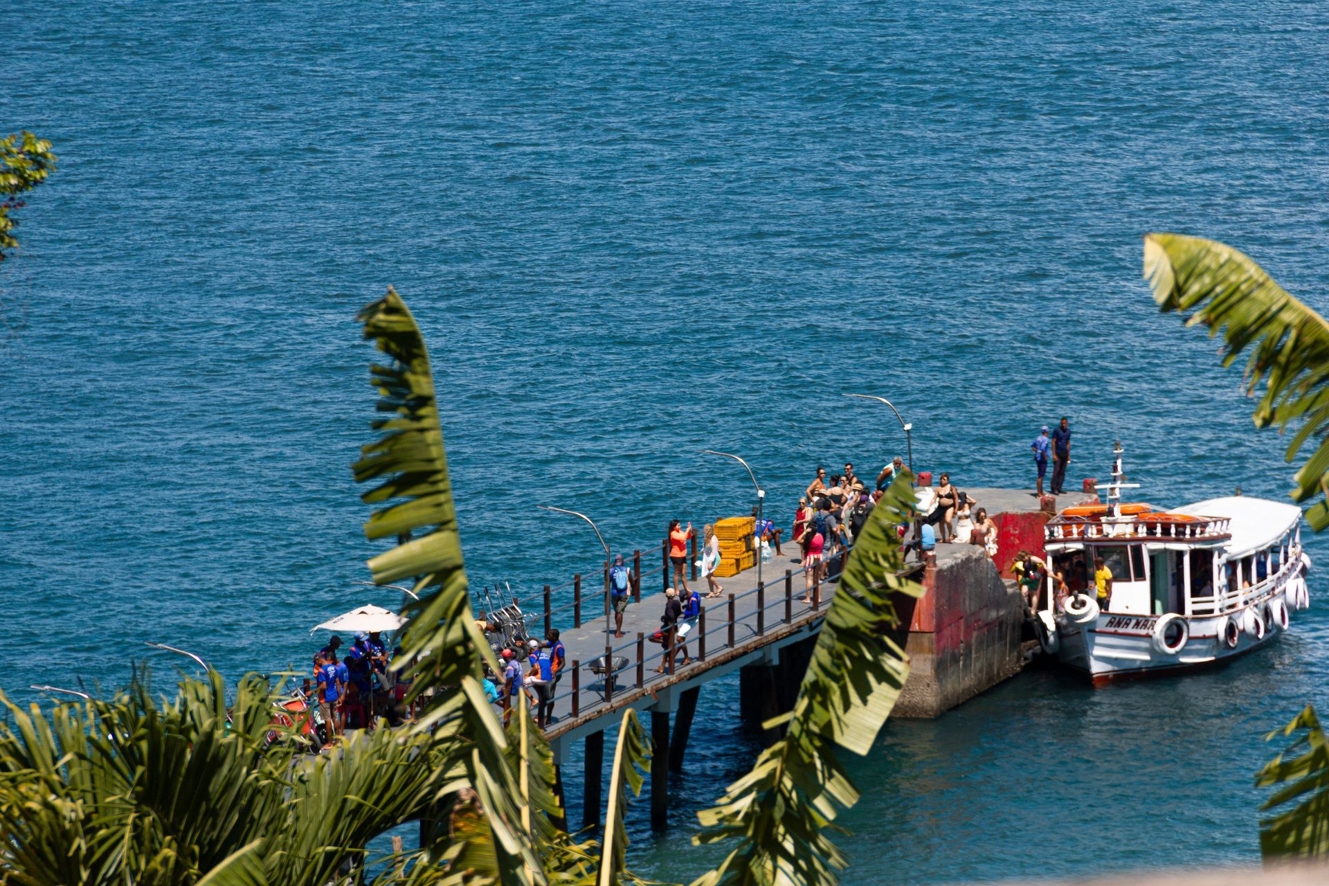 a boat is docked at a pier with people standing on it .