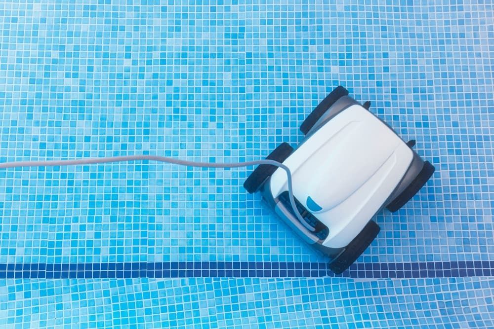 A Robotic Pool Cleaner Moves Across a Tiled Blue Pool Floor