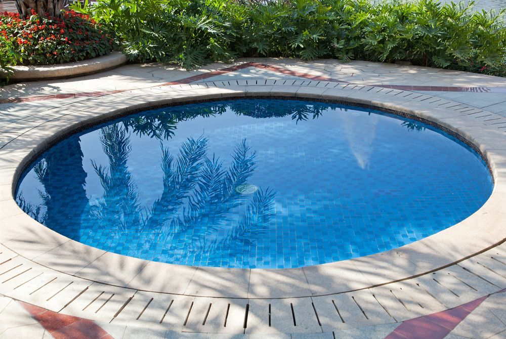 Round Blue Pool Surrounded by a Stone Patio, With Foliage in the Background — Ballina Pool Shop In Byron Bay, NSW