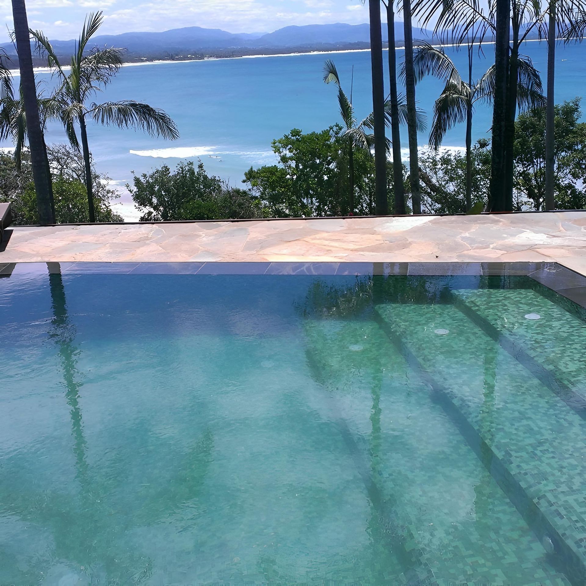 A Swimming Pool With A View Of The Ocean And Palm Trees — Ballina Pool Shop In Ballina, NSW