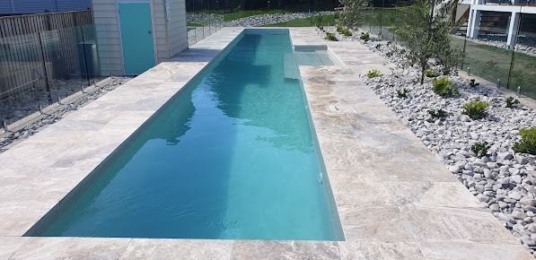 A Long Swimming Pool Surrounded By Rocks And A Fence — Ballina Pool Shop In Evans Head, NSW