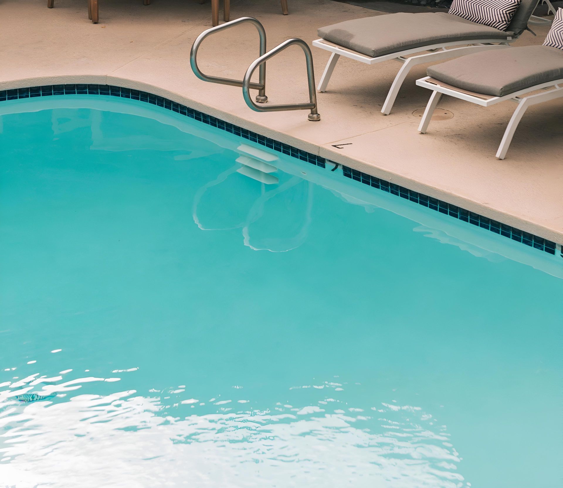 A Large Swimming Pool With A Staircase And Chairs Surrounding It — Ballina Pool Shop In Ballina, NSW