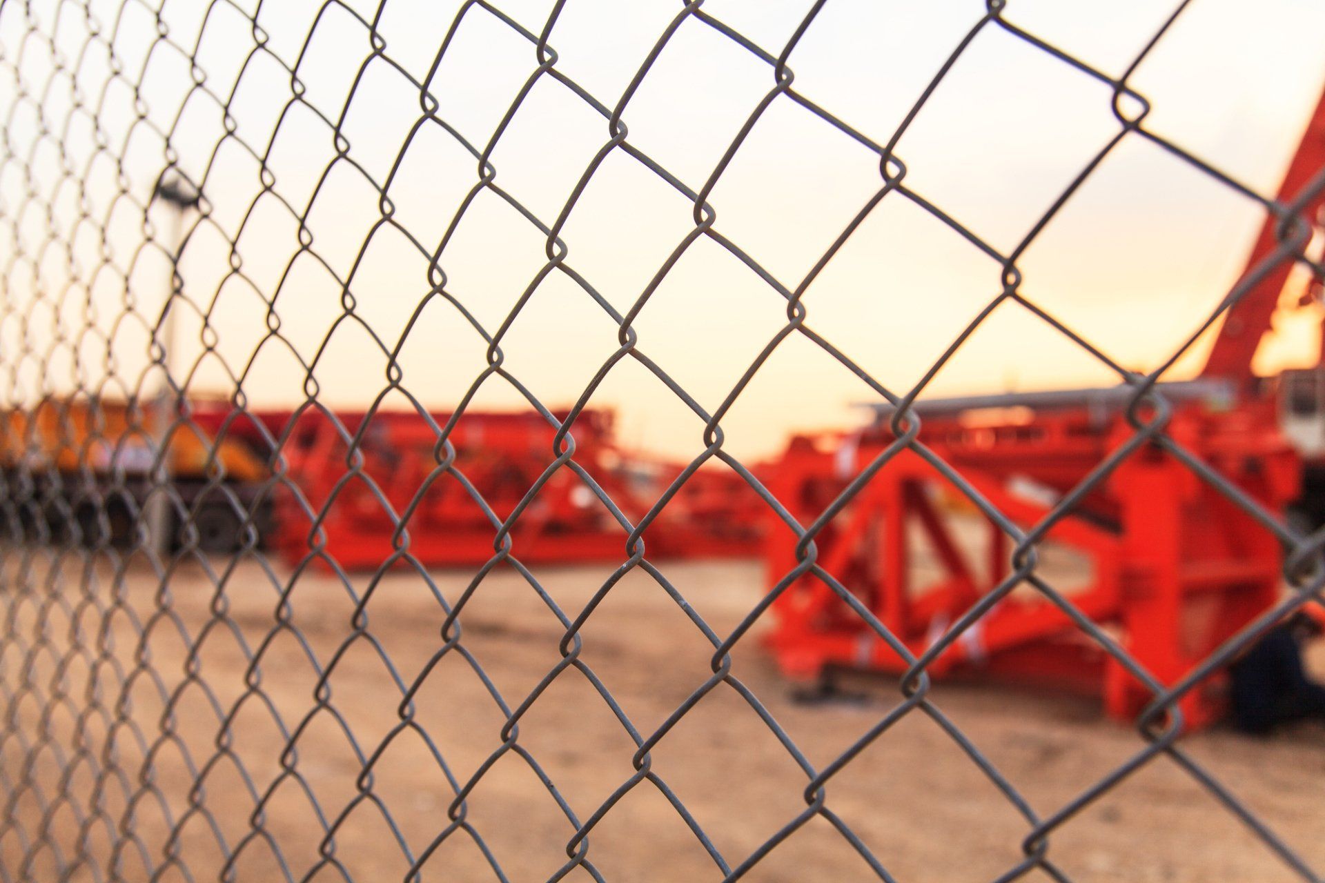 A chain link fence with a blurred background of a construction site.