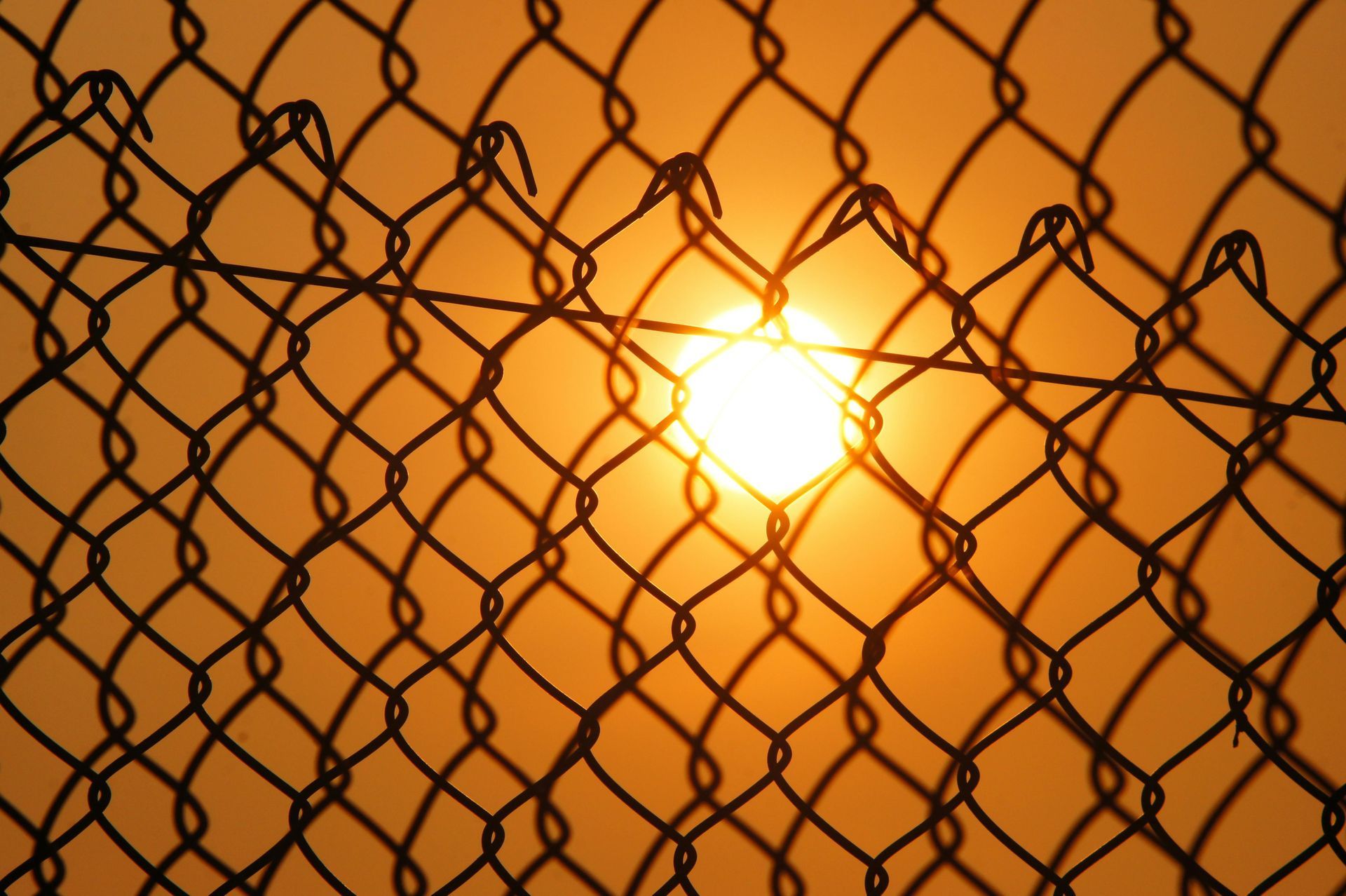 Looking up at a chain link fence against a blue sky