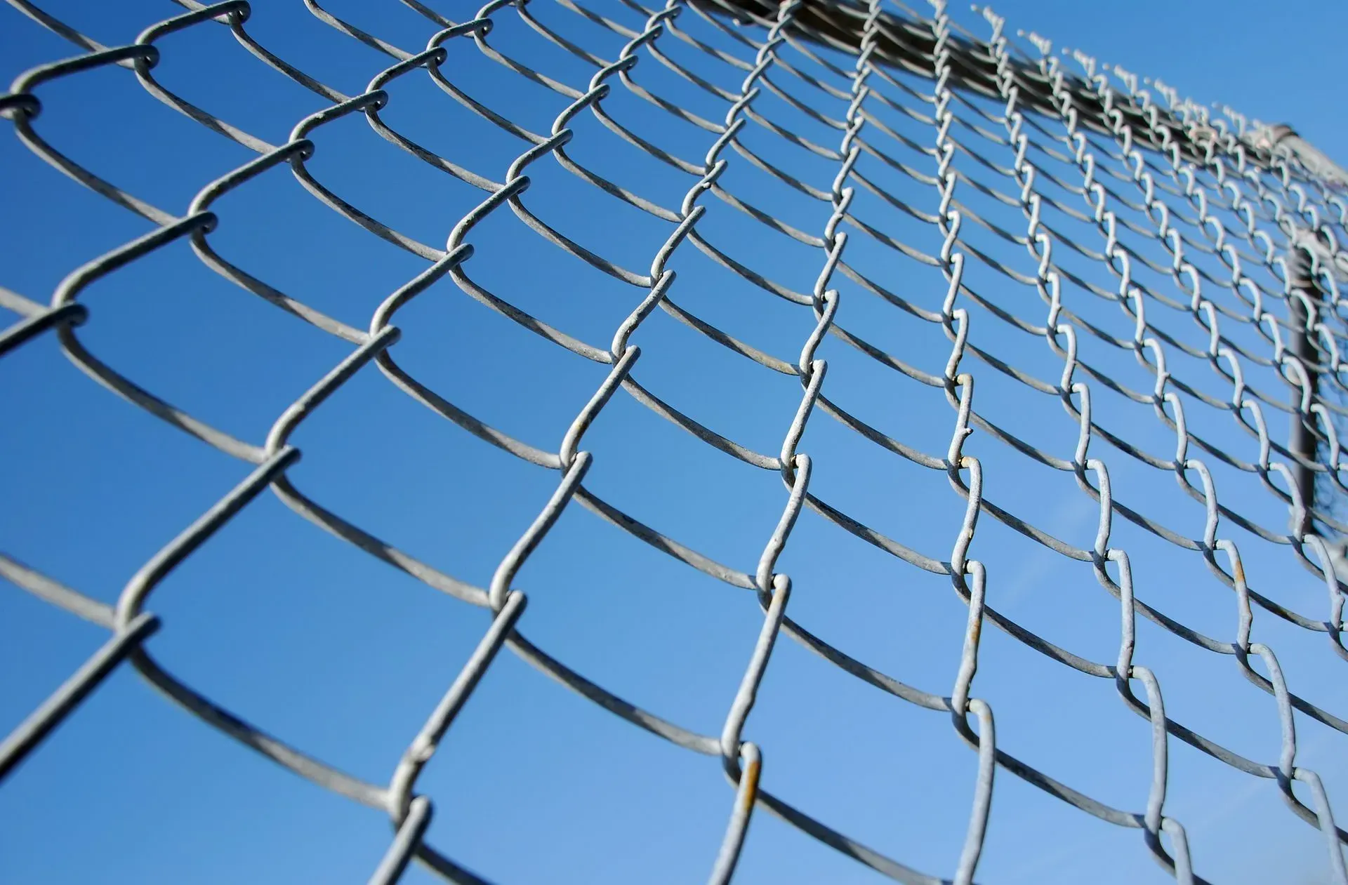 Looking up at a chain link fence against a blue sky