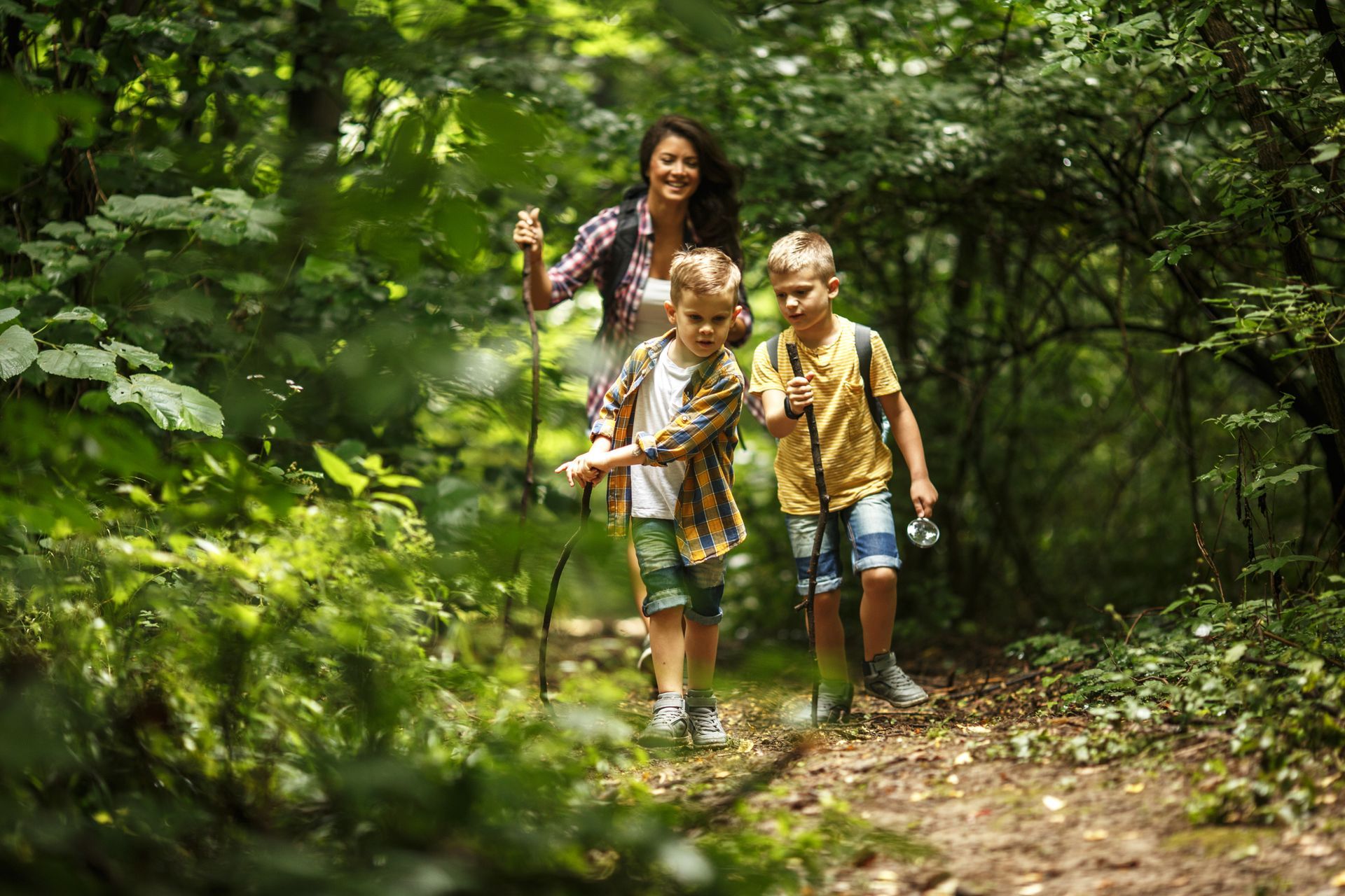 A woman and two children are hiking in the woods.