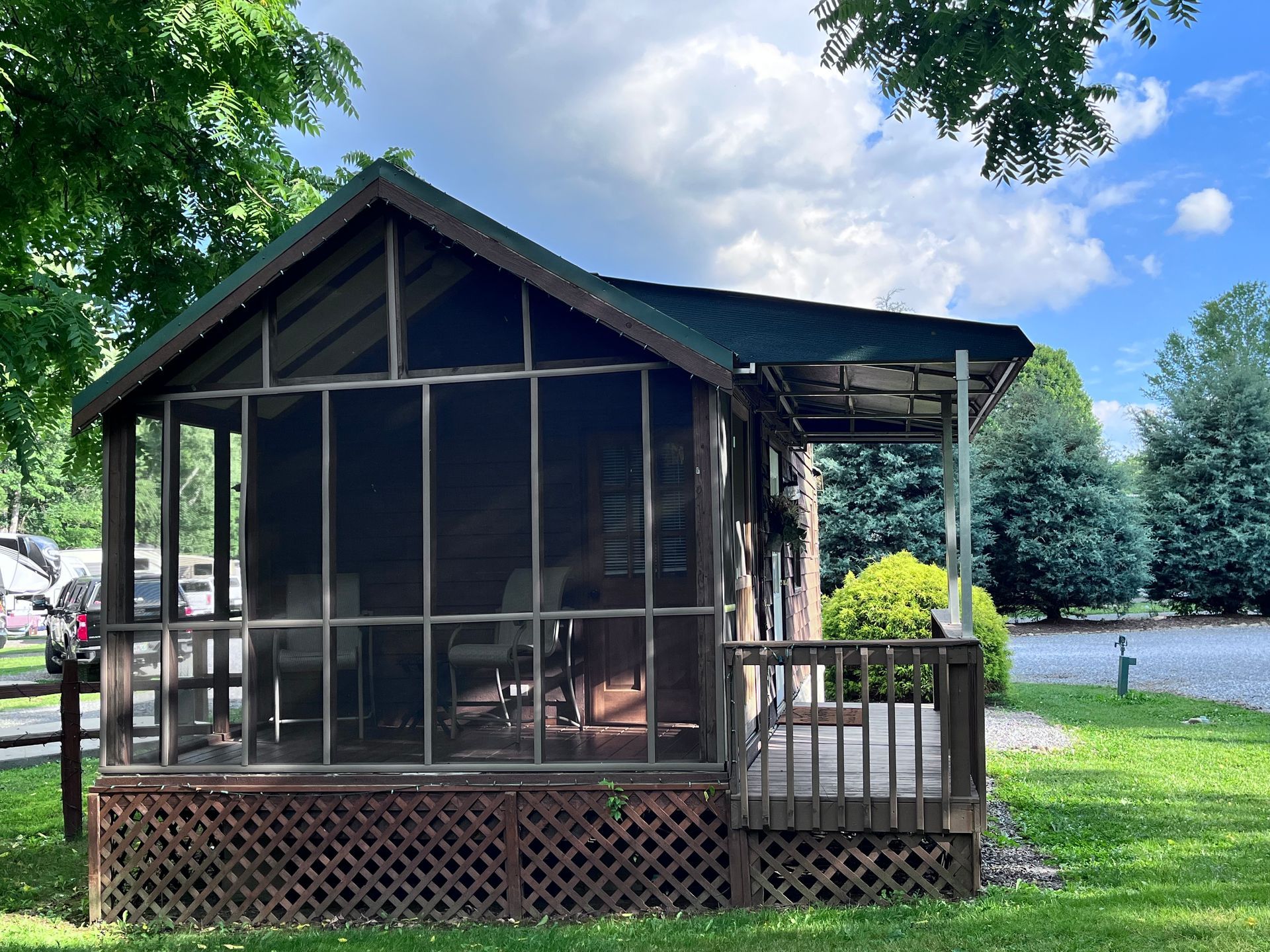 A small house with a screened in porch and a green roof