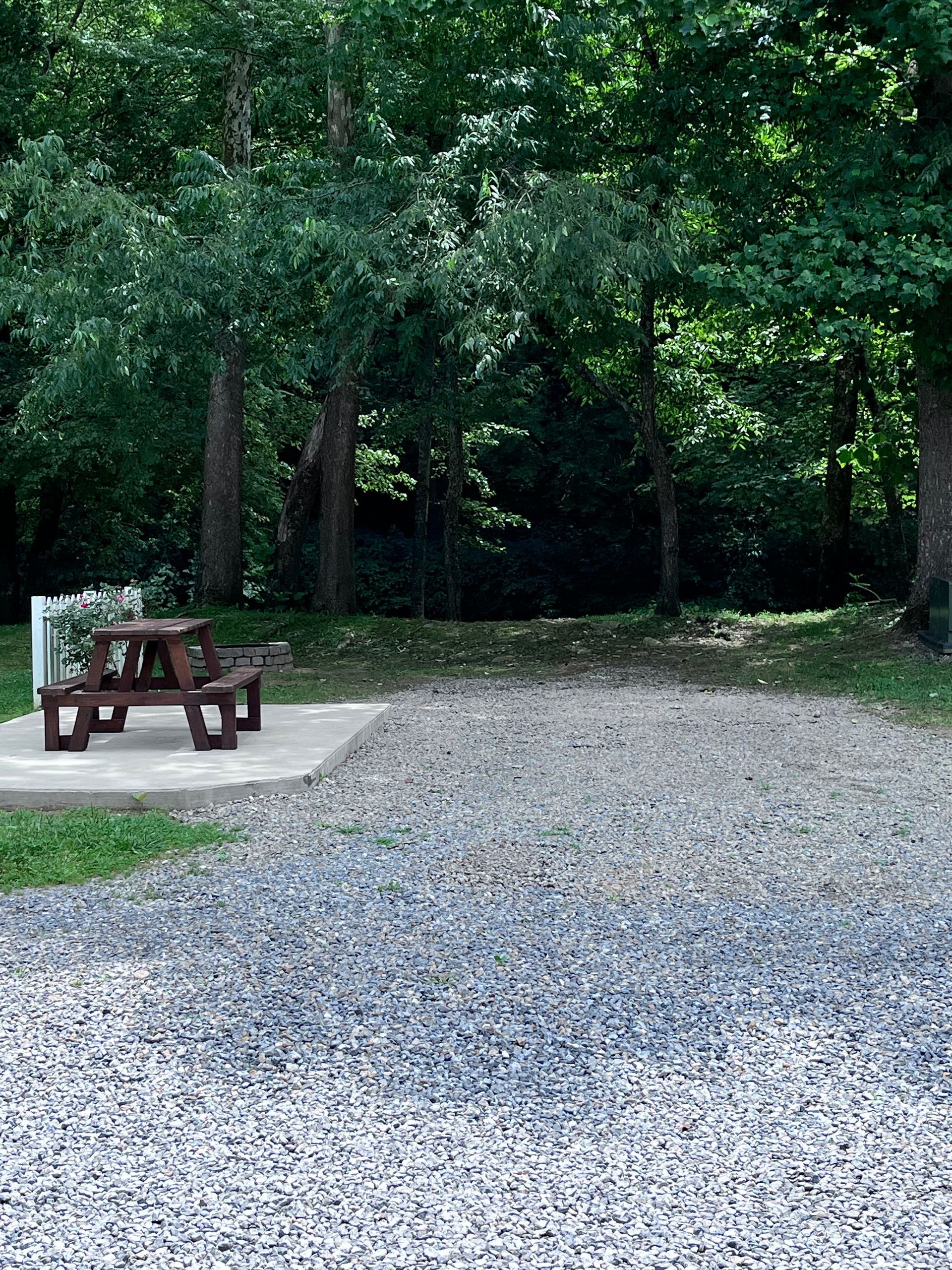 A picnic table in a gravel area with trees in the background