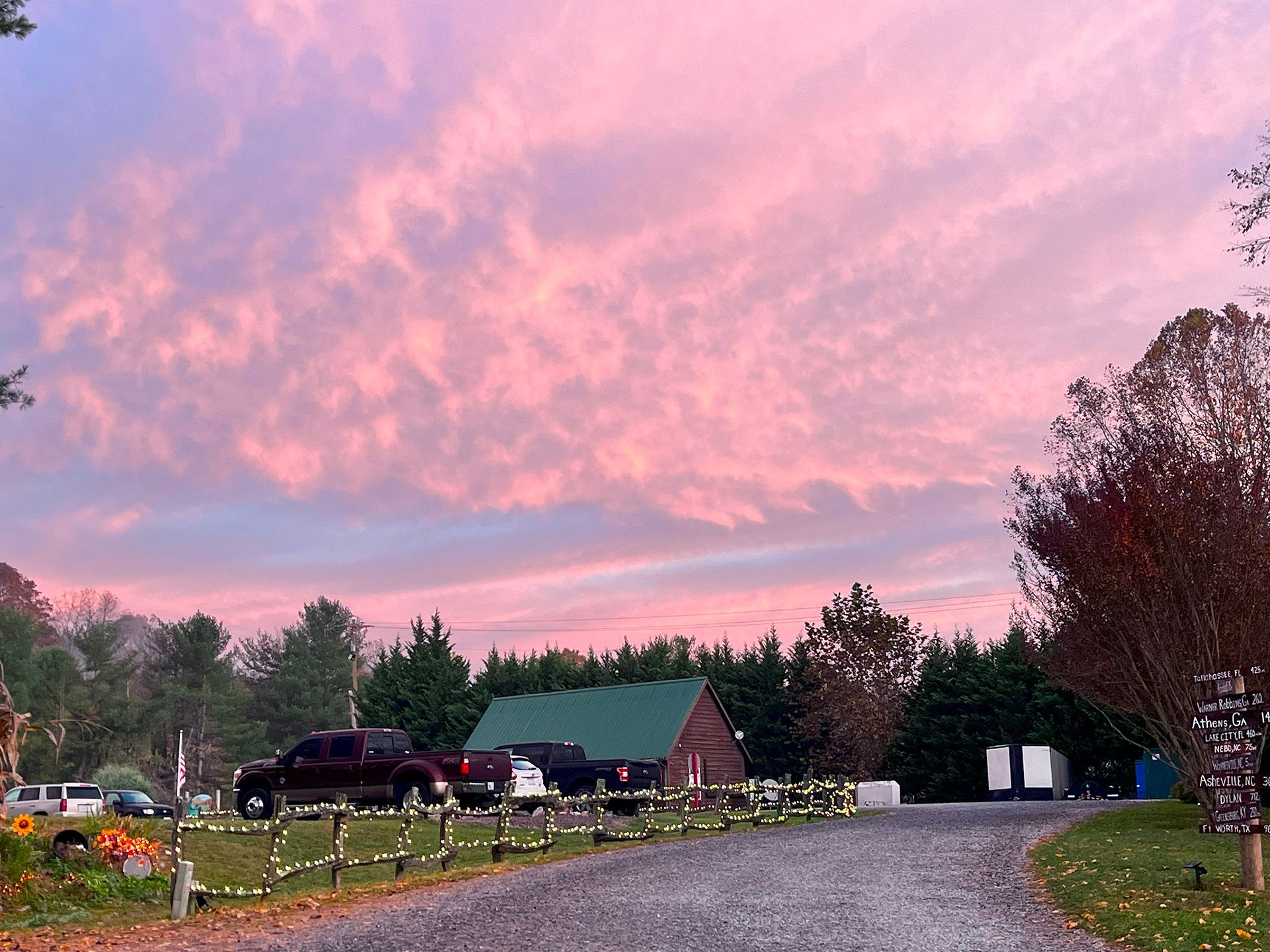 A driveway leading to a house with a pink sky in the background