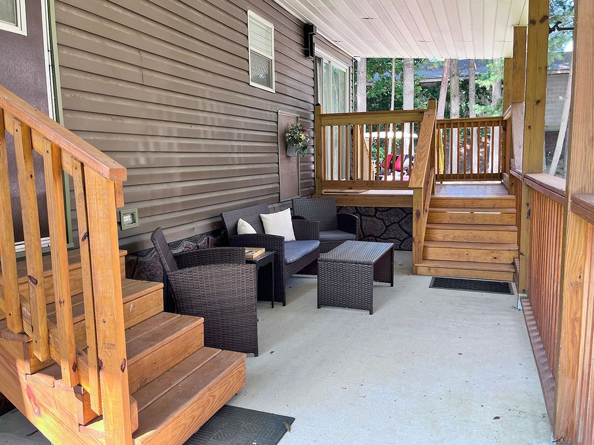 A porch with a couch and chairs and stairs leading up to it