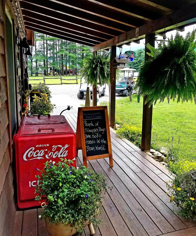 A red coca cola cooler sits on a wooden porch