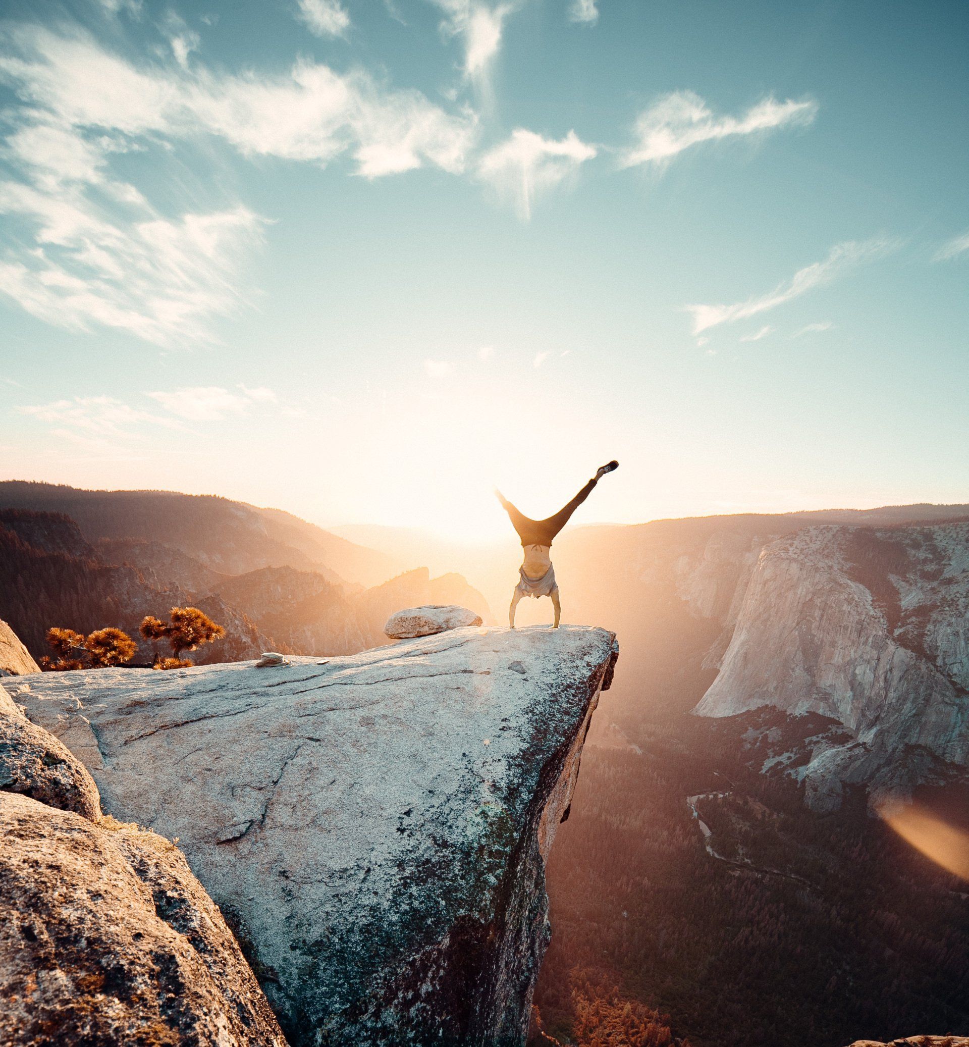 A person is doing a handstand on the edge of a cliff