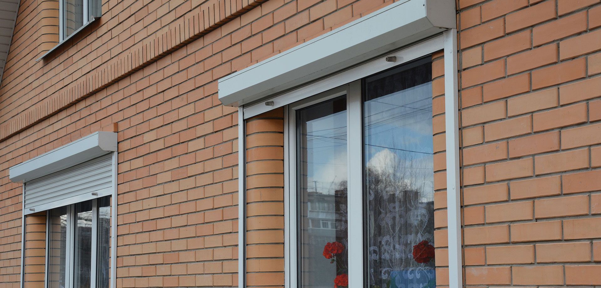 A brick building with a row of windows with roller shutters on them.