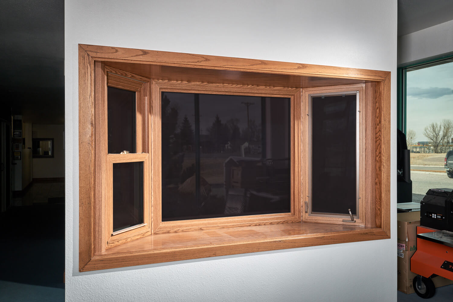 A large wooden window is hanging on a white wall.