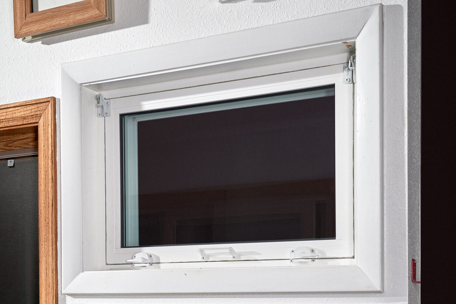 A white window with a wooden frame is hanging on a wall.