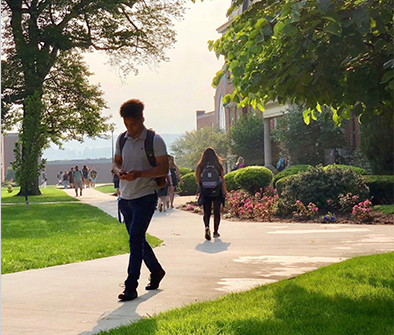 A man with a backpack is walking down a sidewalk