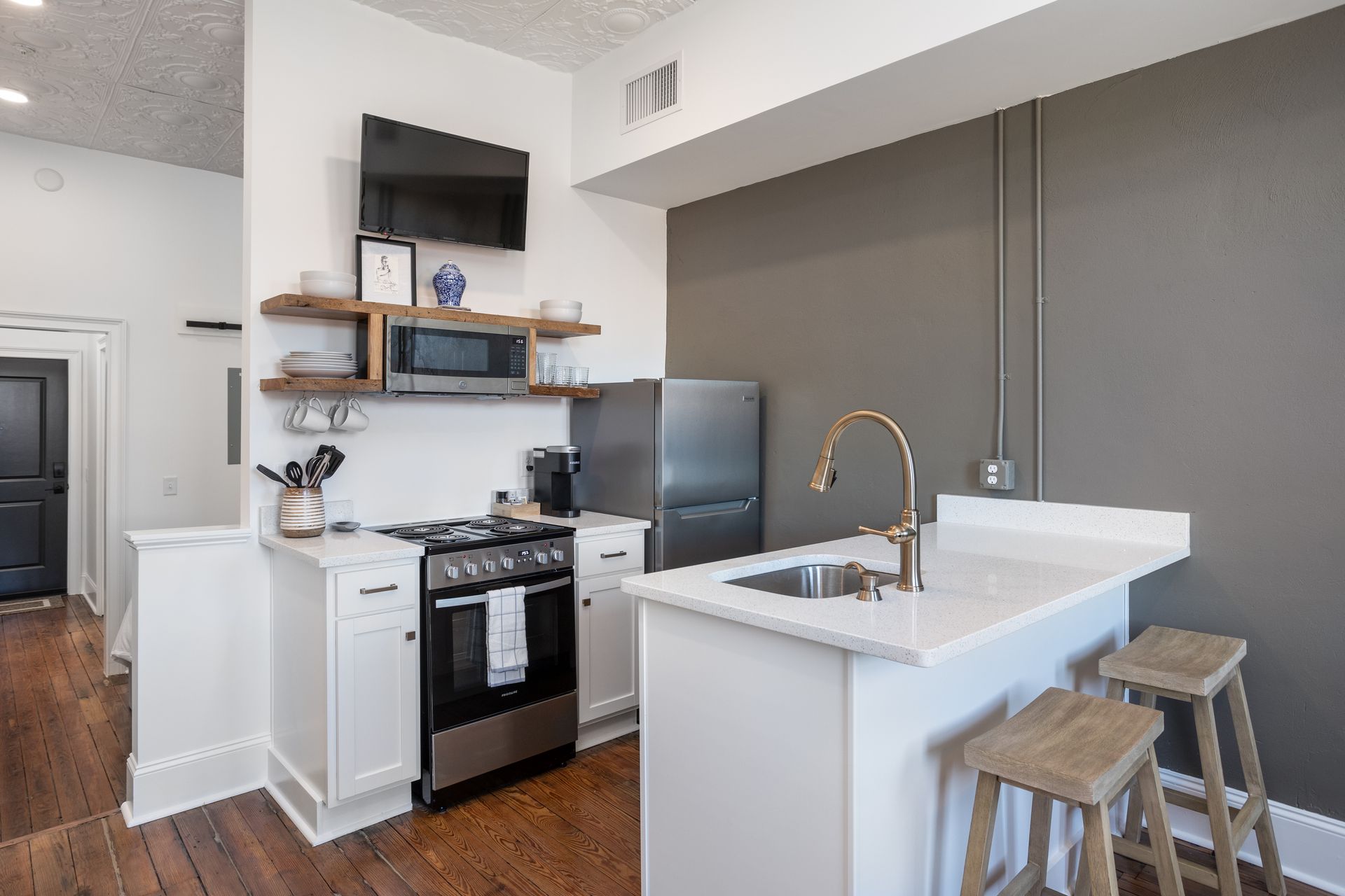 Galley kitchen. with open shelving and wooden bar stools.