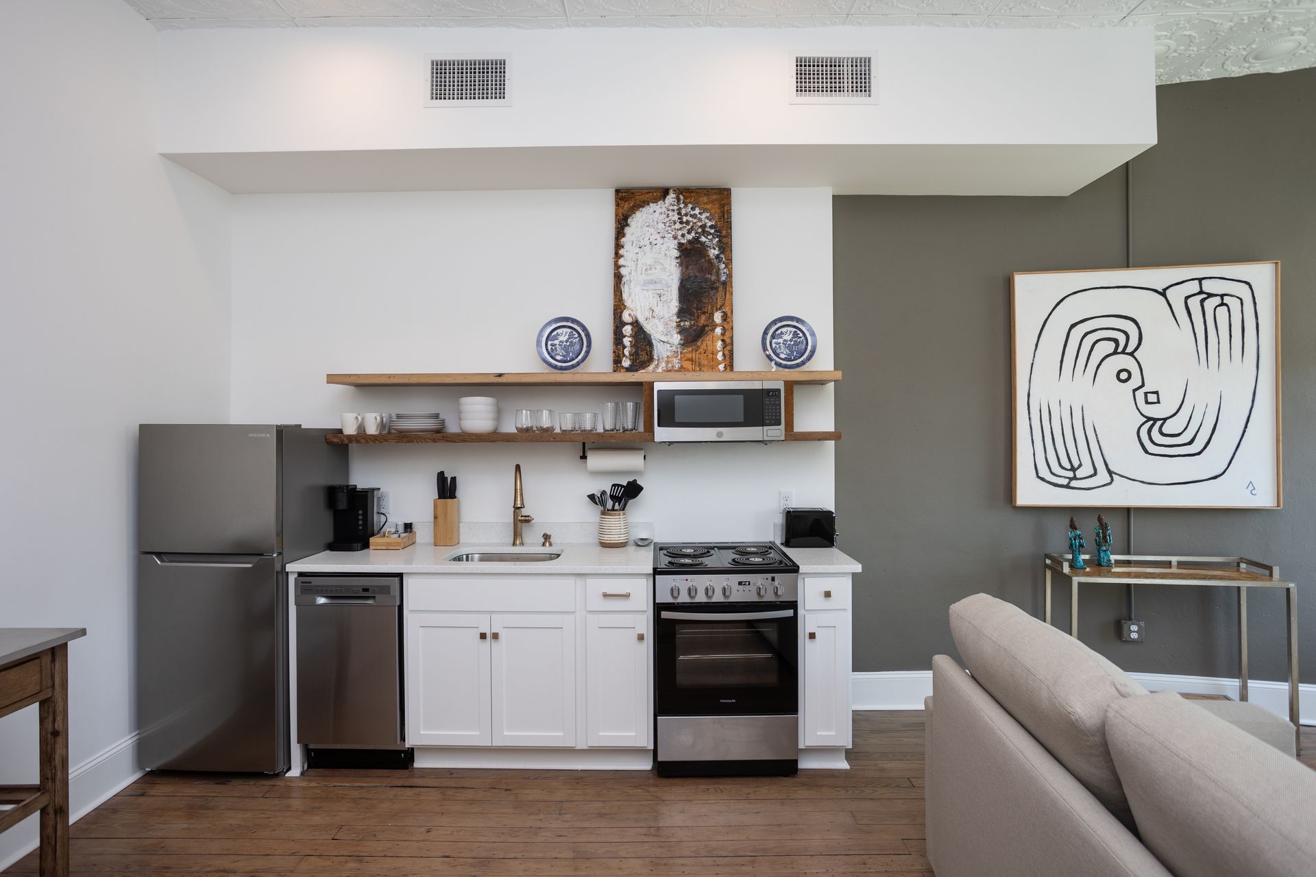 Interior photo of an apartment interior with a tan sofa and galley kitchen.