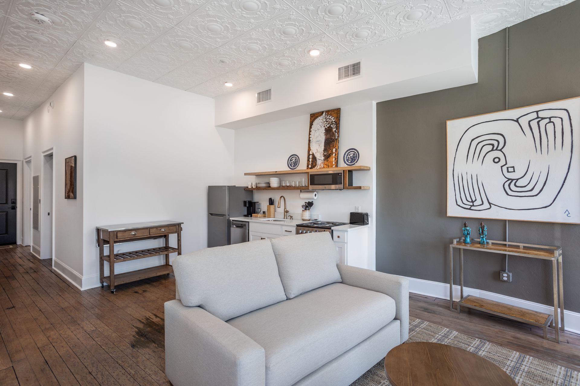 Interior photo of an apartment interior with a tan sofa and galley kitchen.