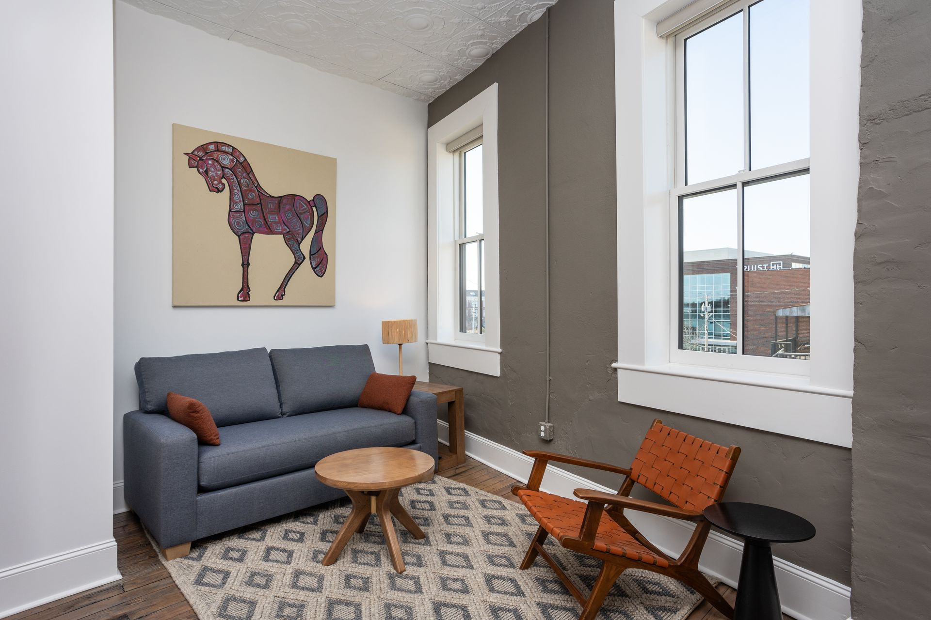 Living area with sofa and chair. Horse painting on the wall.