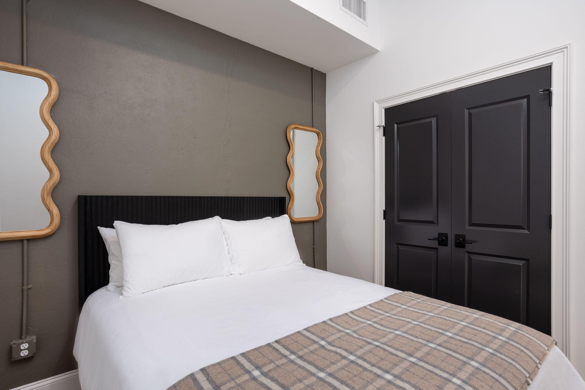Queen size bed and mirrors on a wall.