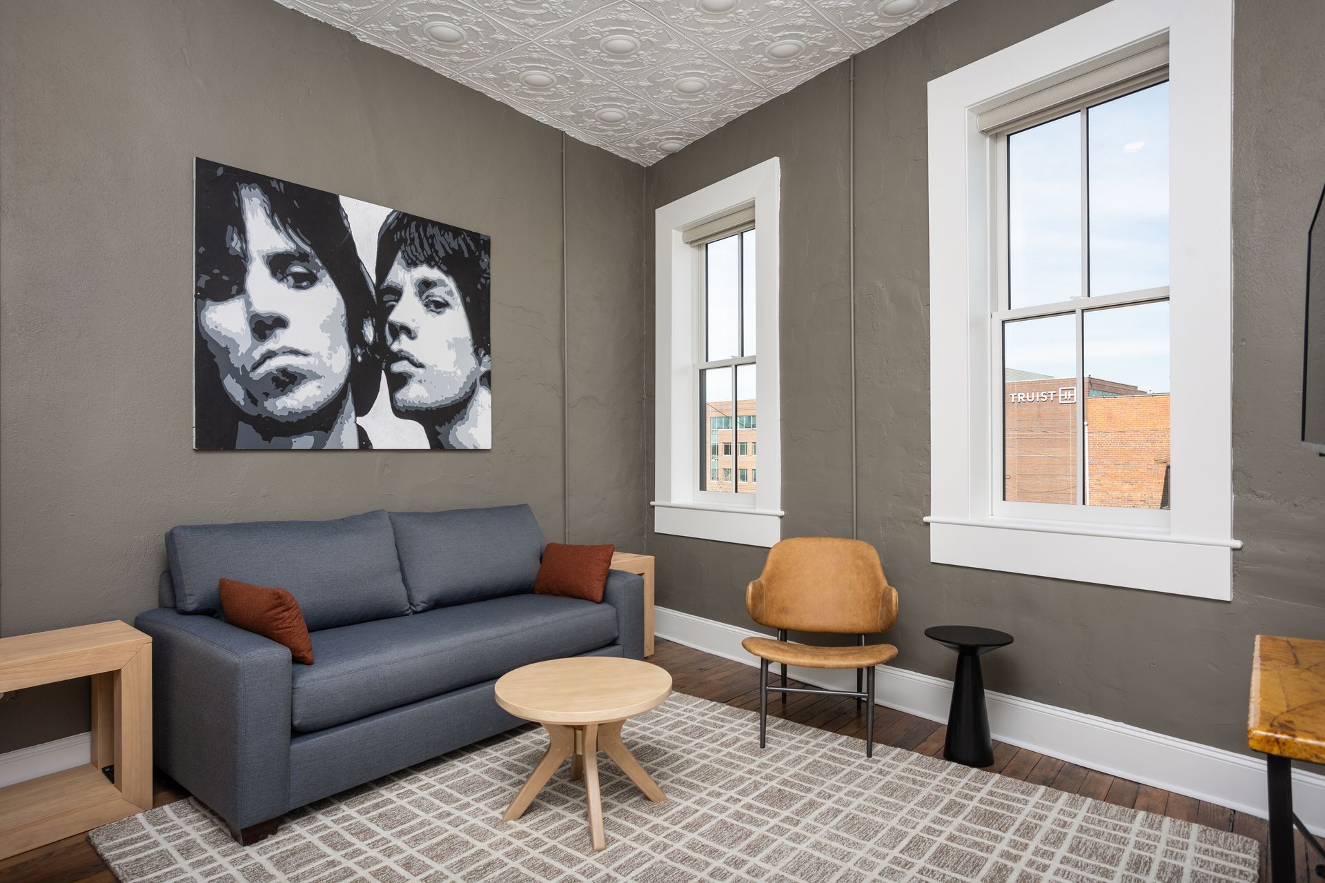Living room with a blue sofa and painting of two men.