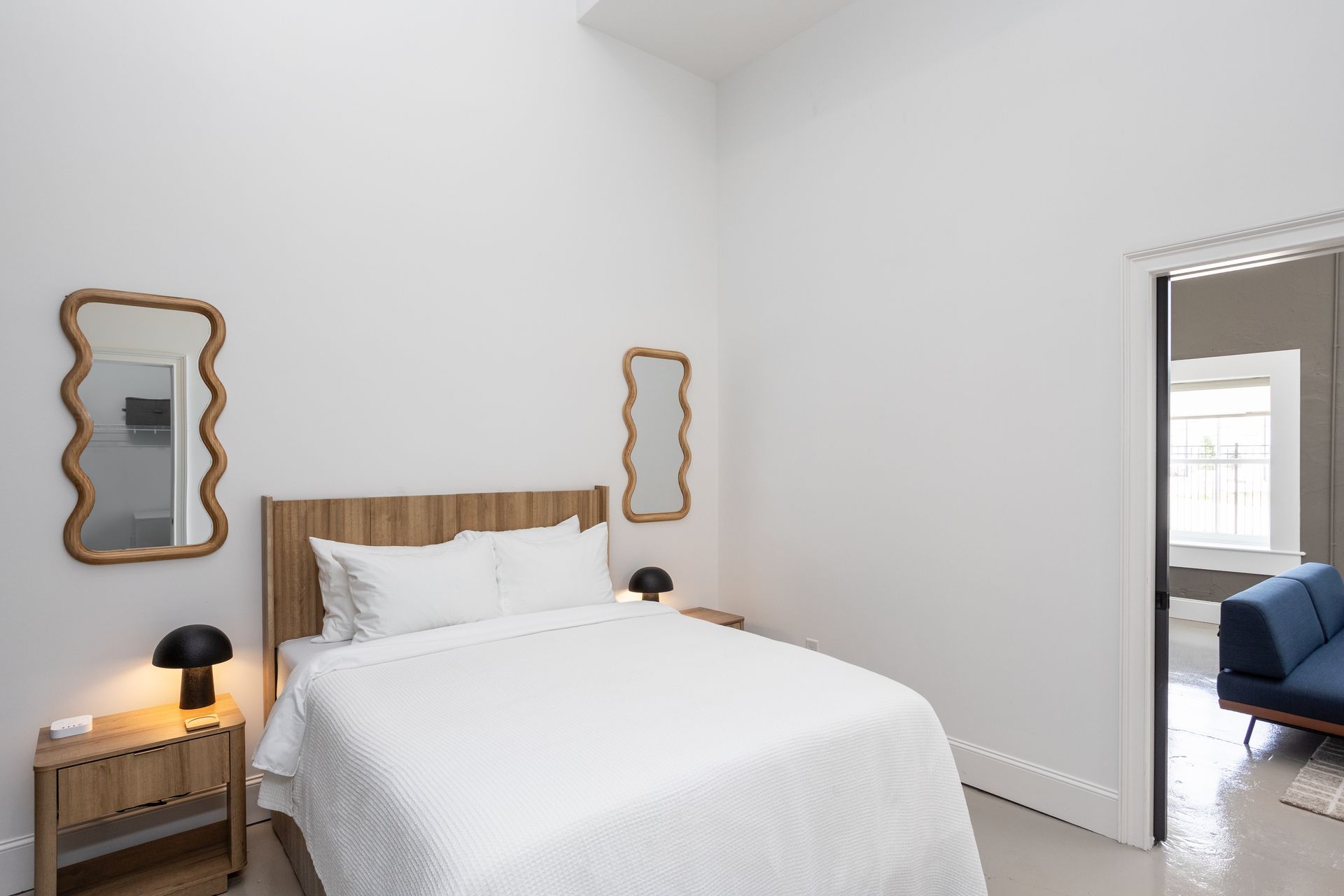 Queen size bed with two wavy mirrors on the wall