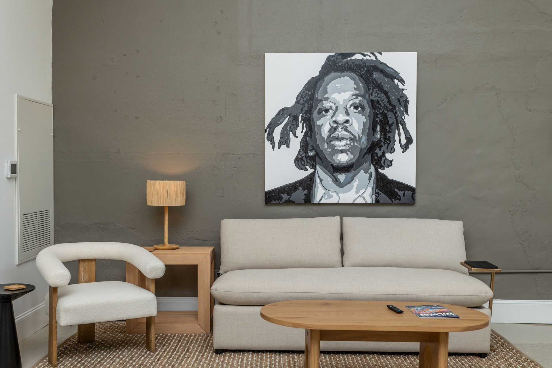 Living area with sofa, chair, coffee table, chair, and photo of Jay Z.