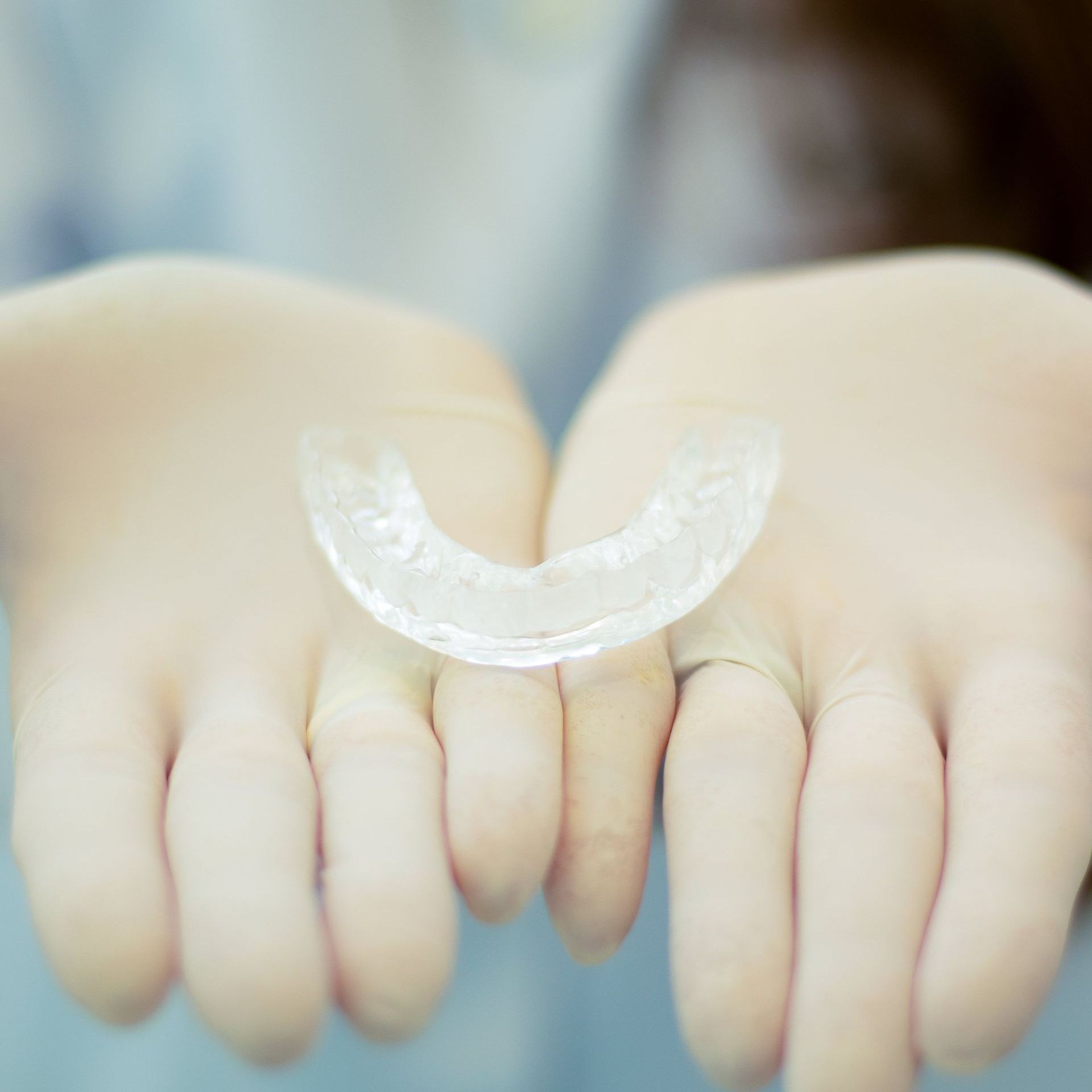 A person is holding a clear mouth guard in their hands.