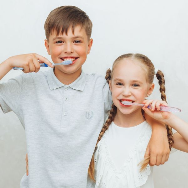 A boy and a girl are brushing their teeth together