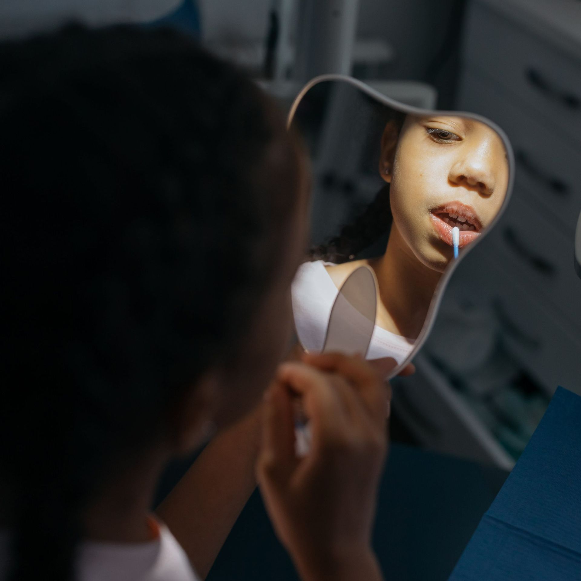 A woman is applying lipstick in front of a mirror