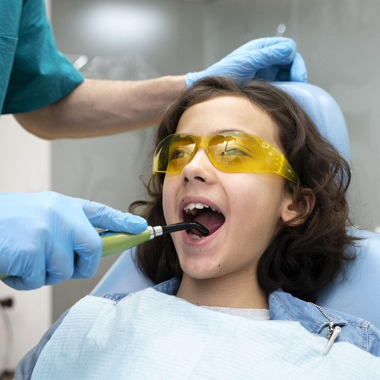 A young girl is getting her teeth examined by a dentist.