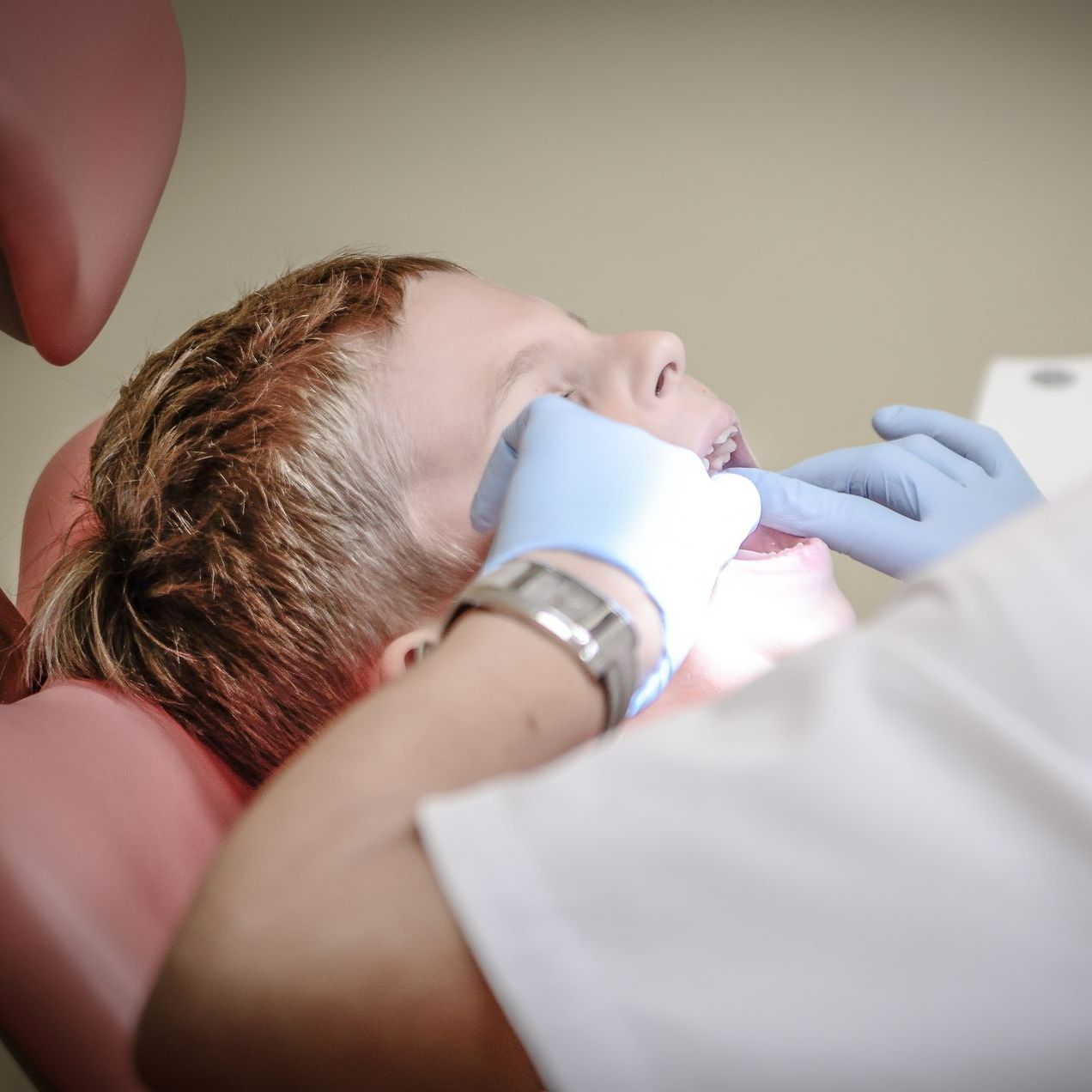 A young boy is getting his teeth examined by a dentist