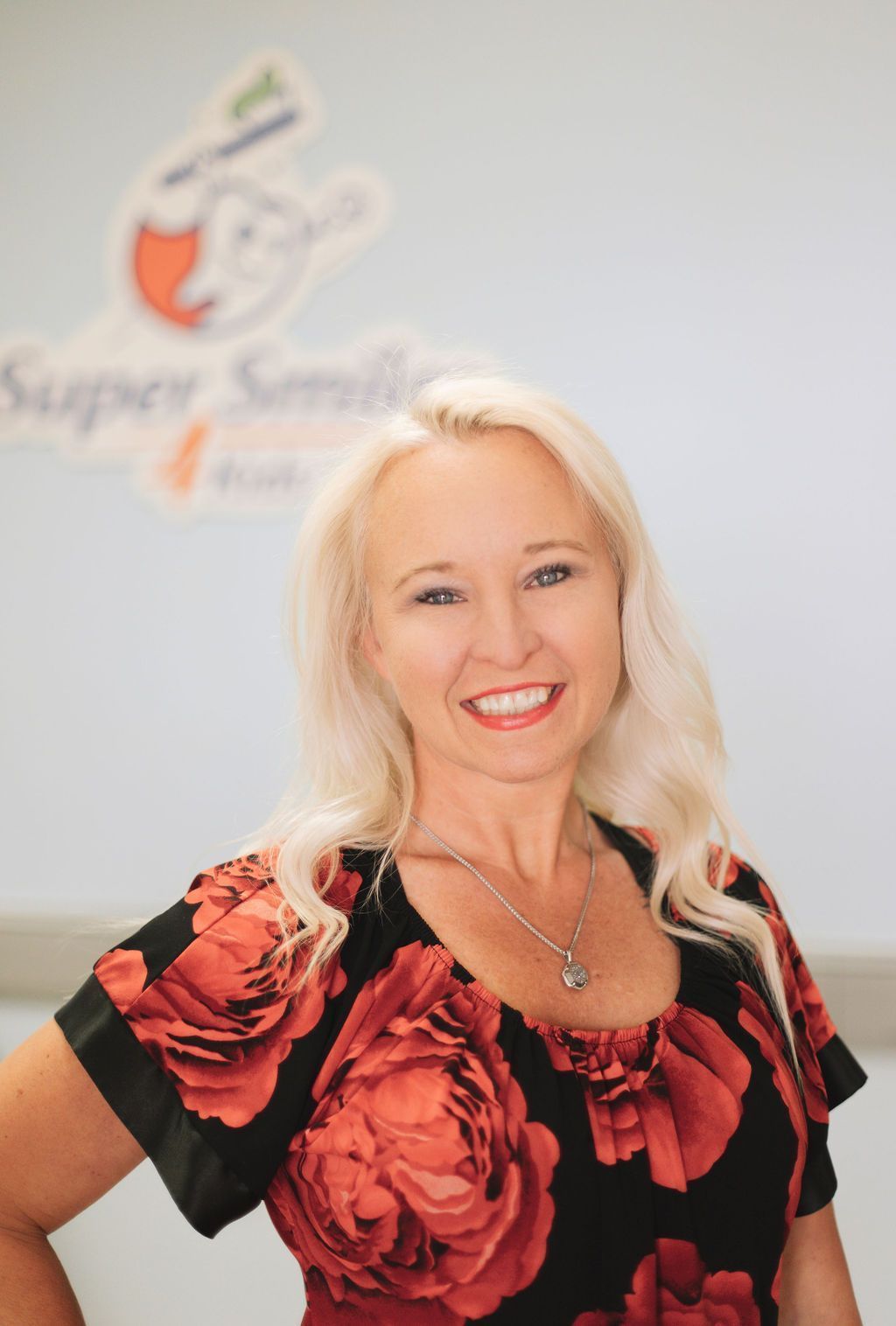 A woman in a red and black floral shirt is smiling for the camera.