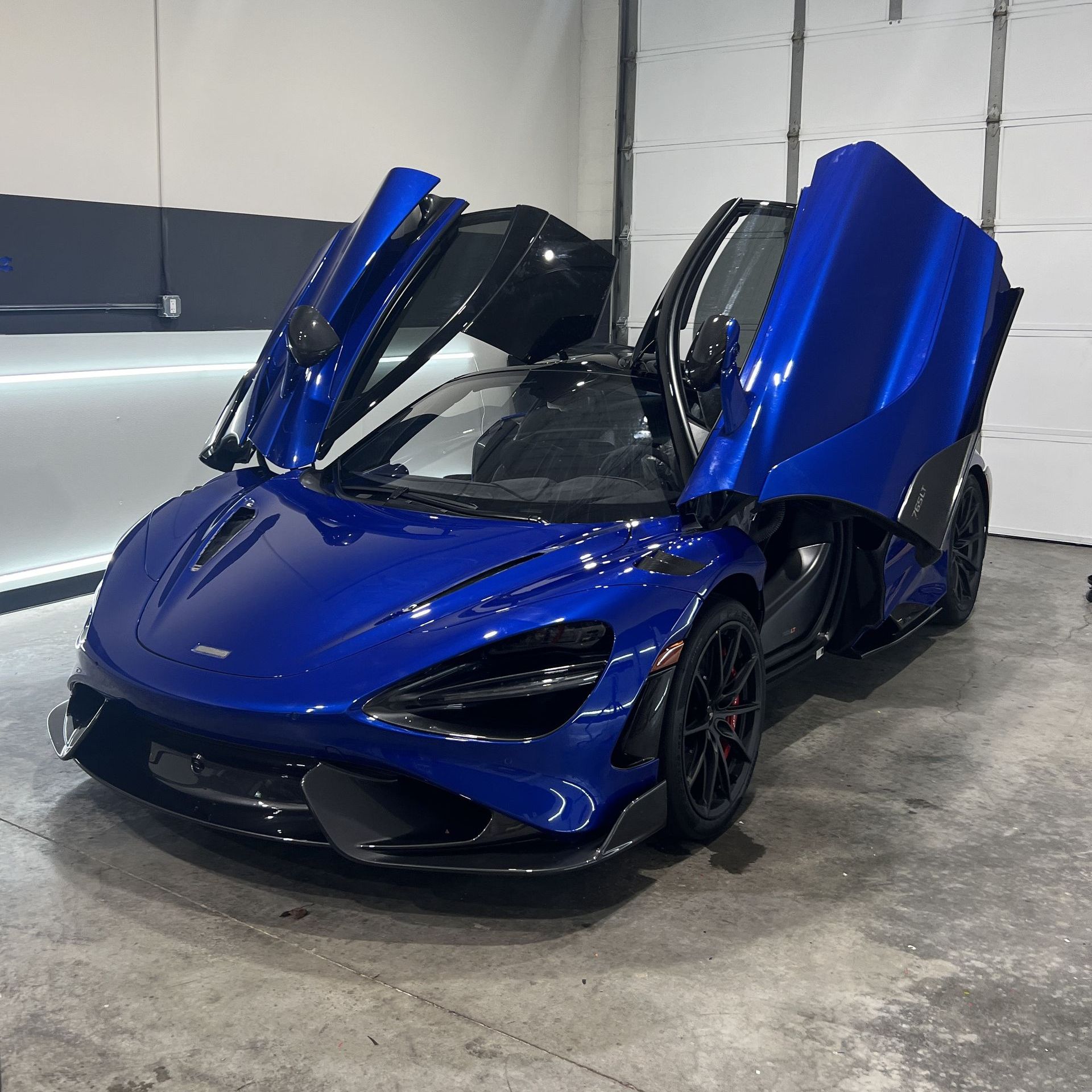 a blue sports car is parked in a garage with its doors open