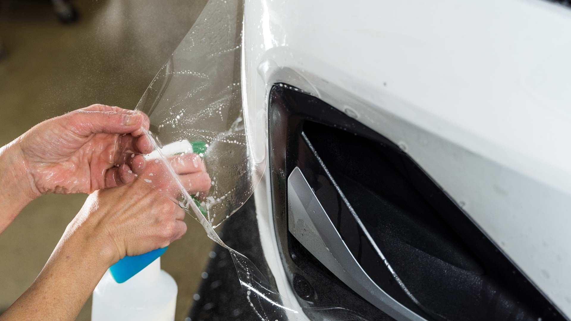 Satin Paint Protection Film - A person is cleaning a car with a spray bottle