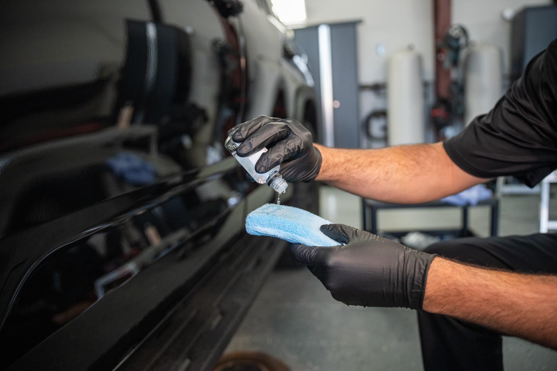 Ceramic Coating - A man wearing black gloves is applying a liquid to a blue sponge