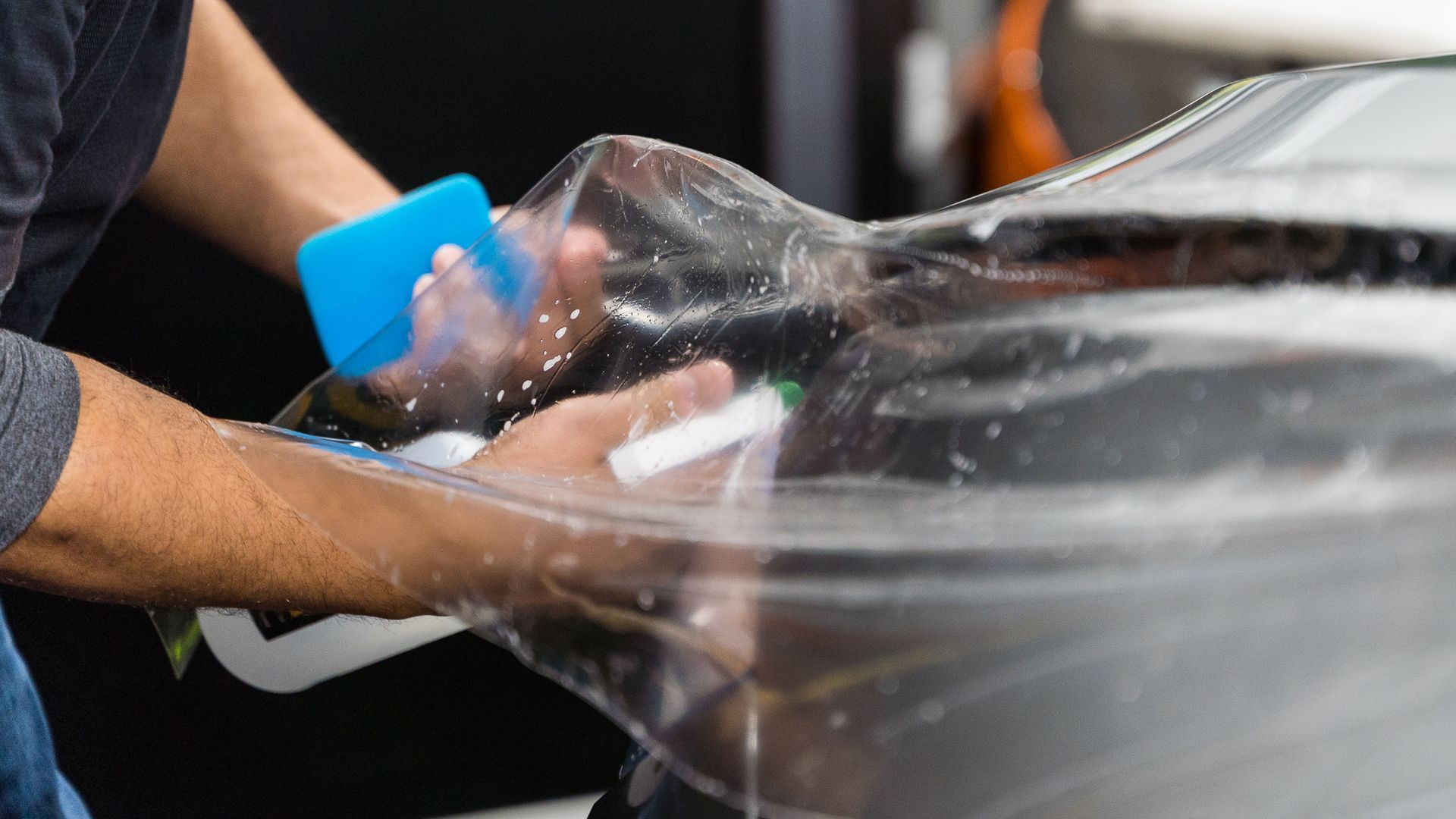 Satin Paint Protection Film - A man is wrapping a car with clear plastic