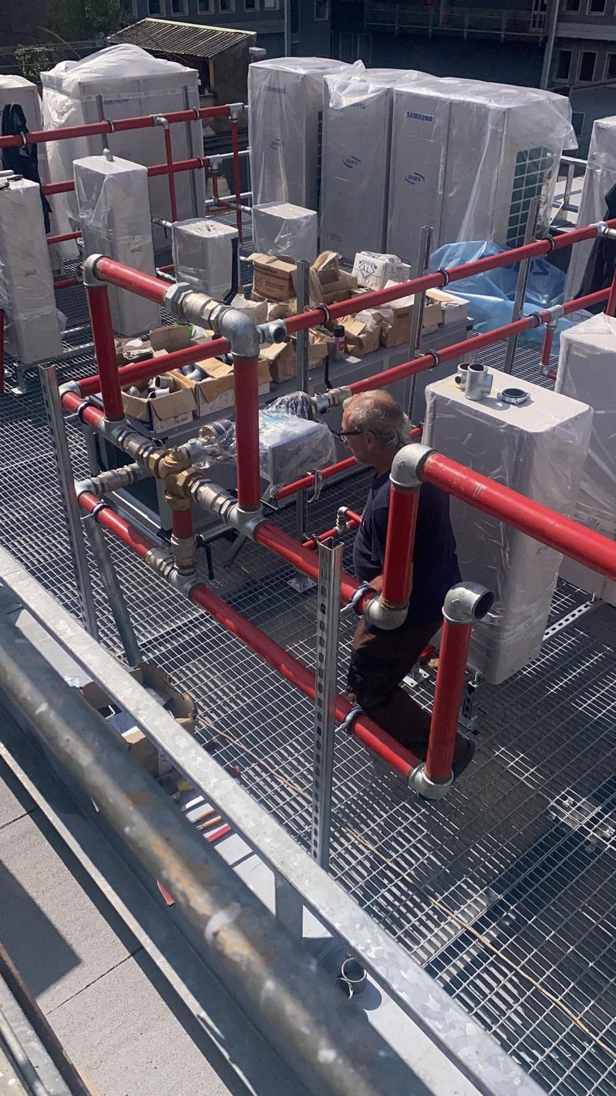 Un uomo sta lavorando su un tetto con tubi e scatole.