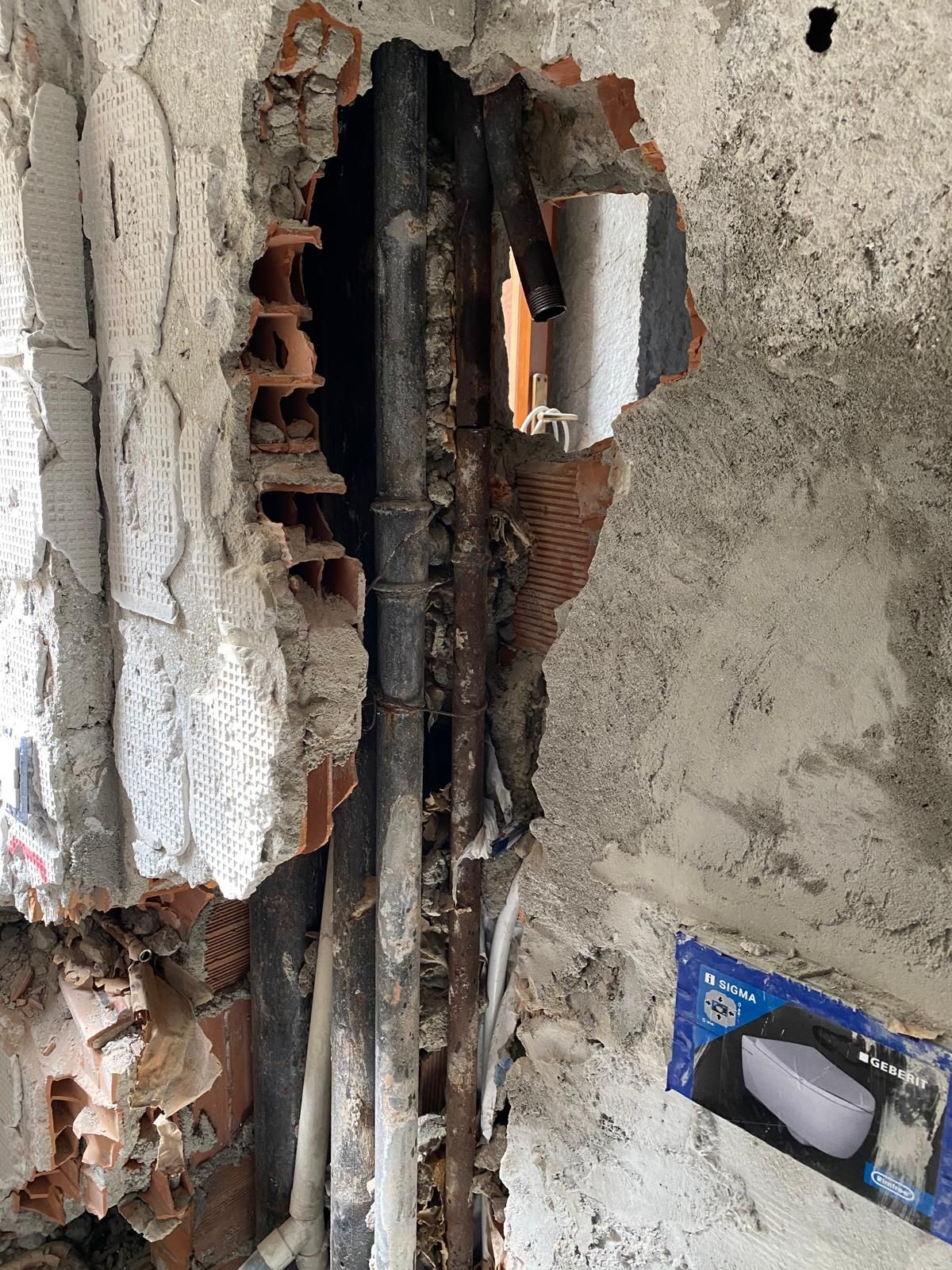 Un buco nel muro da cui escono dei tubi.