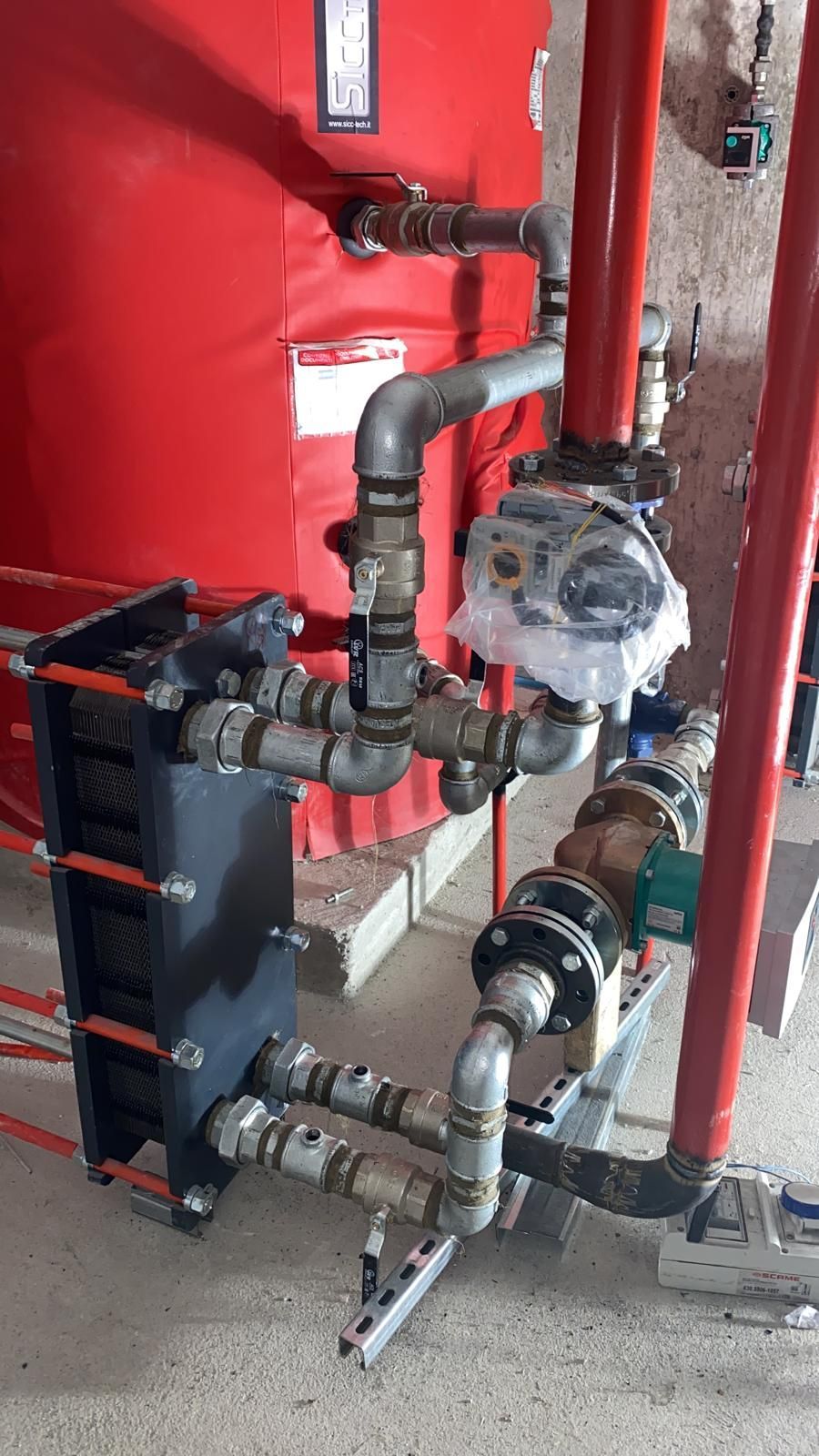 Un gruppo di tubi è collegato a un serbatoio rosso.