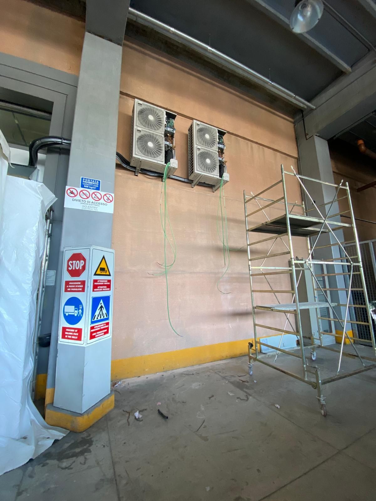 Di fronte a un muro c'è un'impalcatura con sopra due condizionatori.