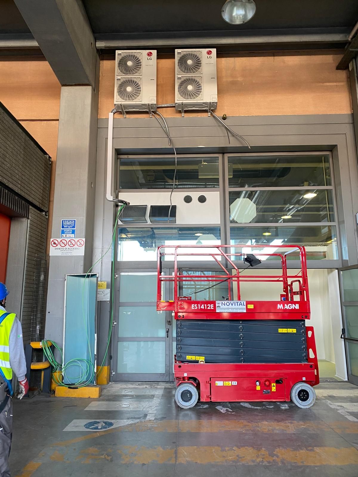 Una piattaforma elevatrice rossa è parcheggiata davanti a un edificio.
