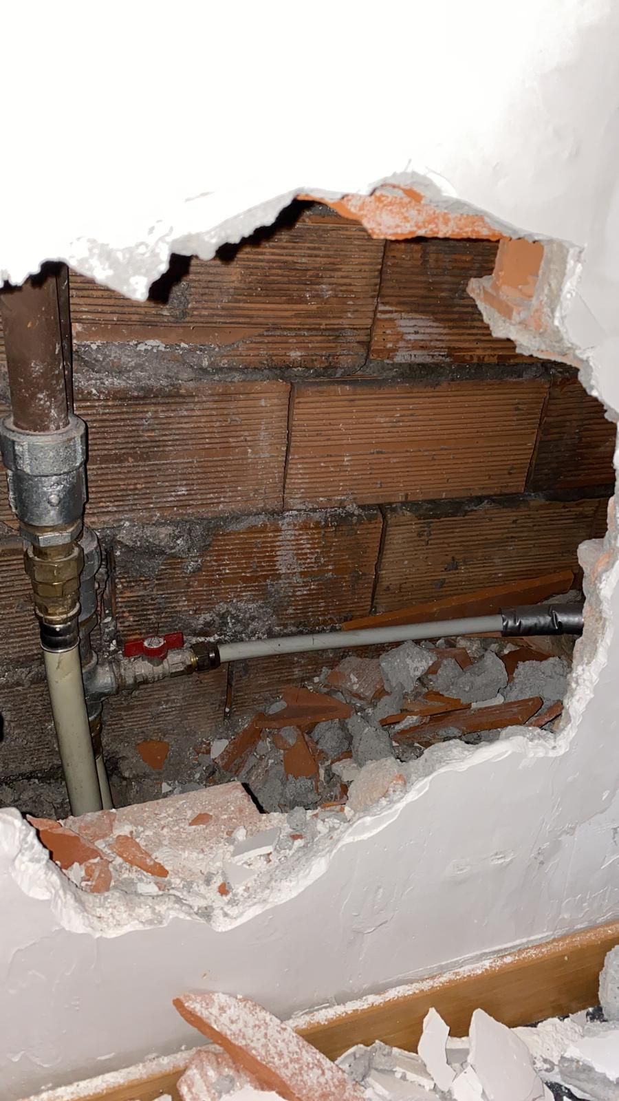 Un buco in un muro di mattoni da cui esce un tubo.