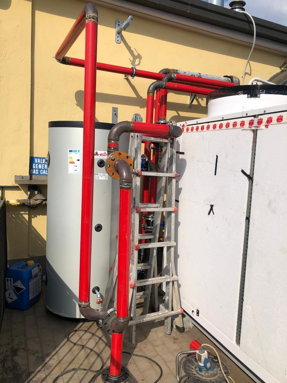 Una scala è appoggiata a un muro accanto a uno scaldabagno