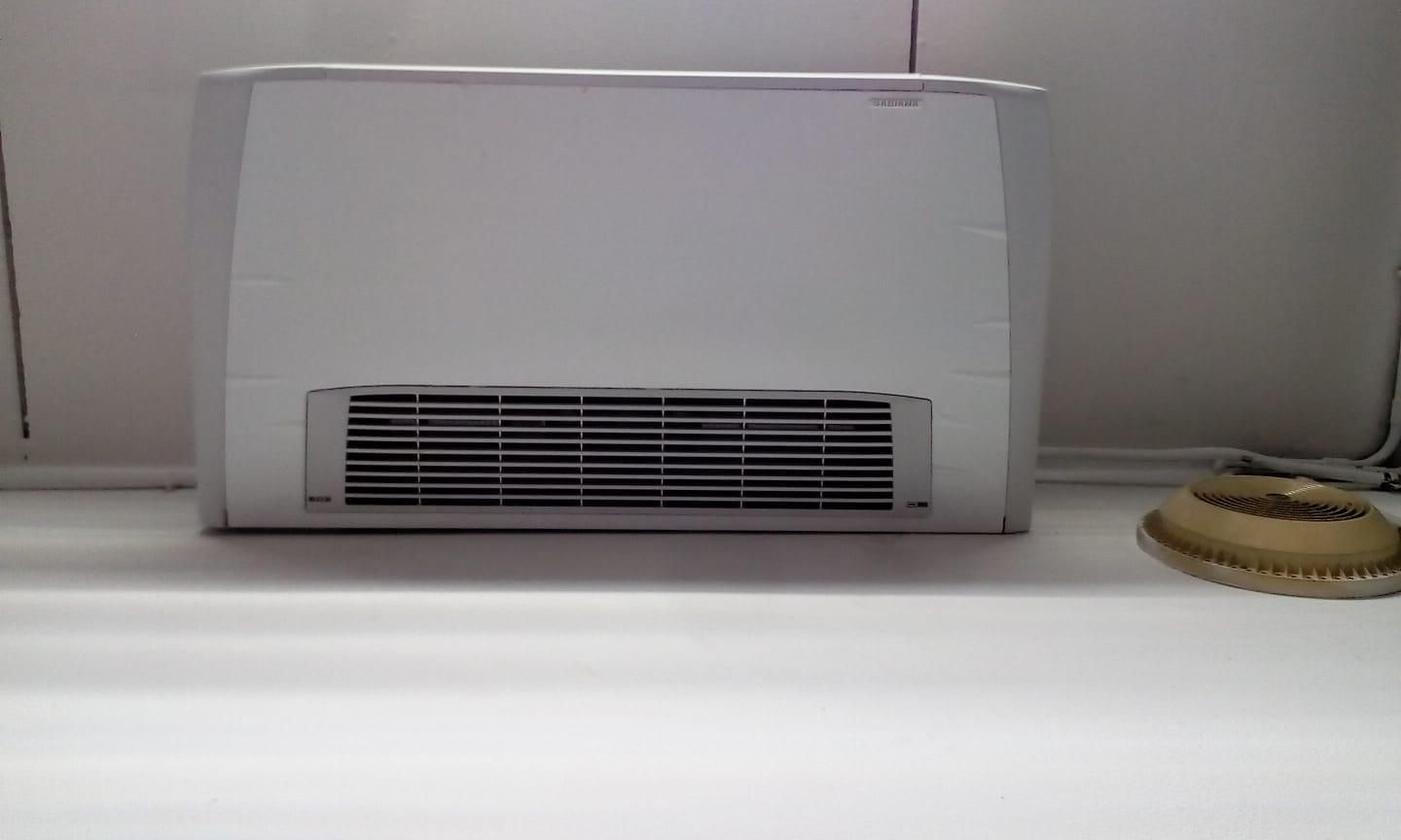 Un frigorifero bianco è appoggiato su un bancone bianco accanto a una lampada.