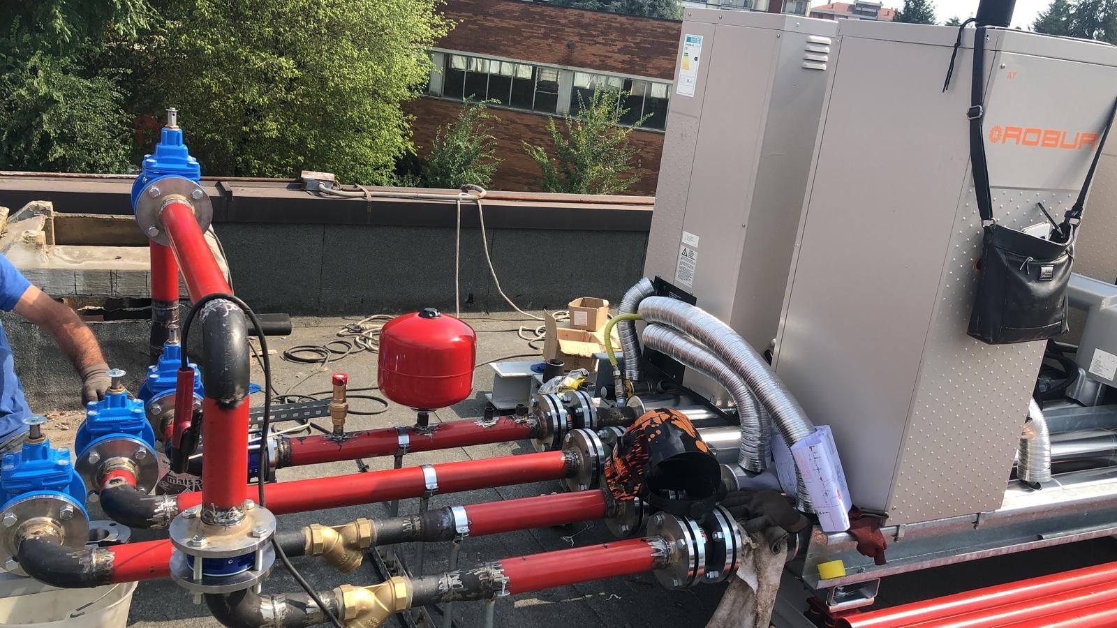 Un uomo sta lavorando su un sistema di tubi su un tetto.