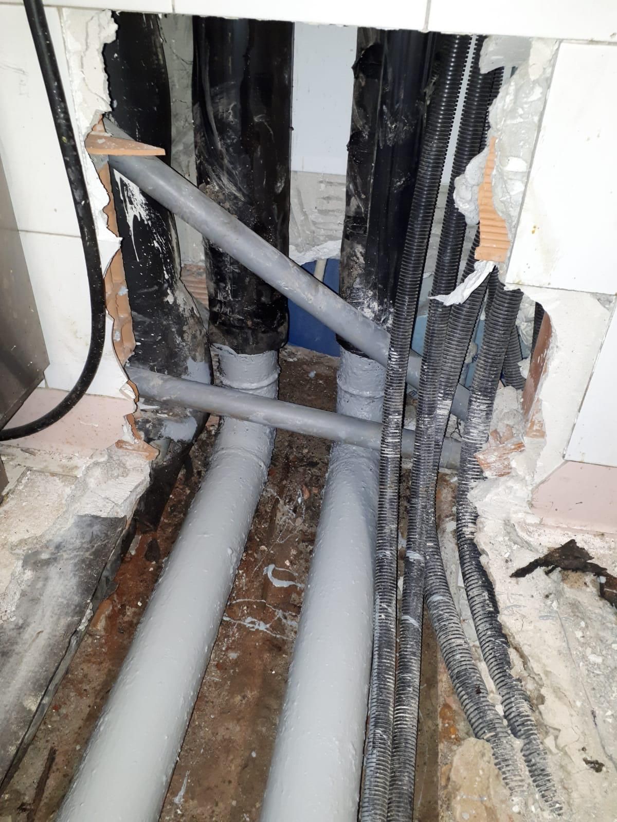 Un mucchio di tubi escono da un buco nel muro.