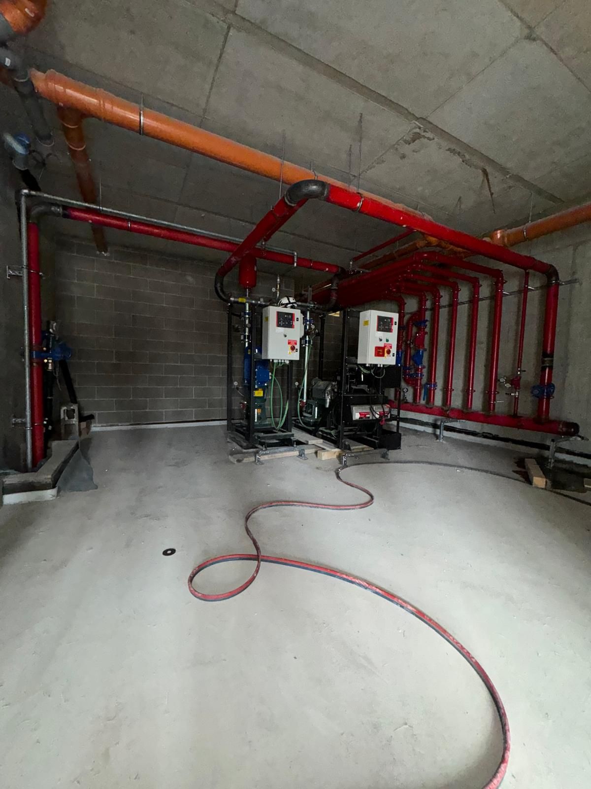 Una stanza con un sacco di tubi e un tubo flessibile che pende dal soffitto.